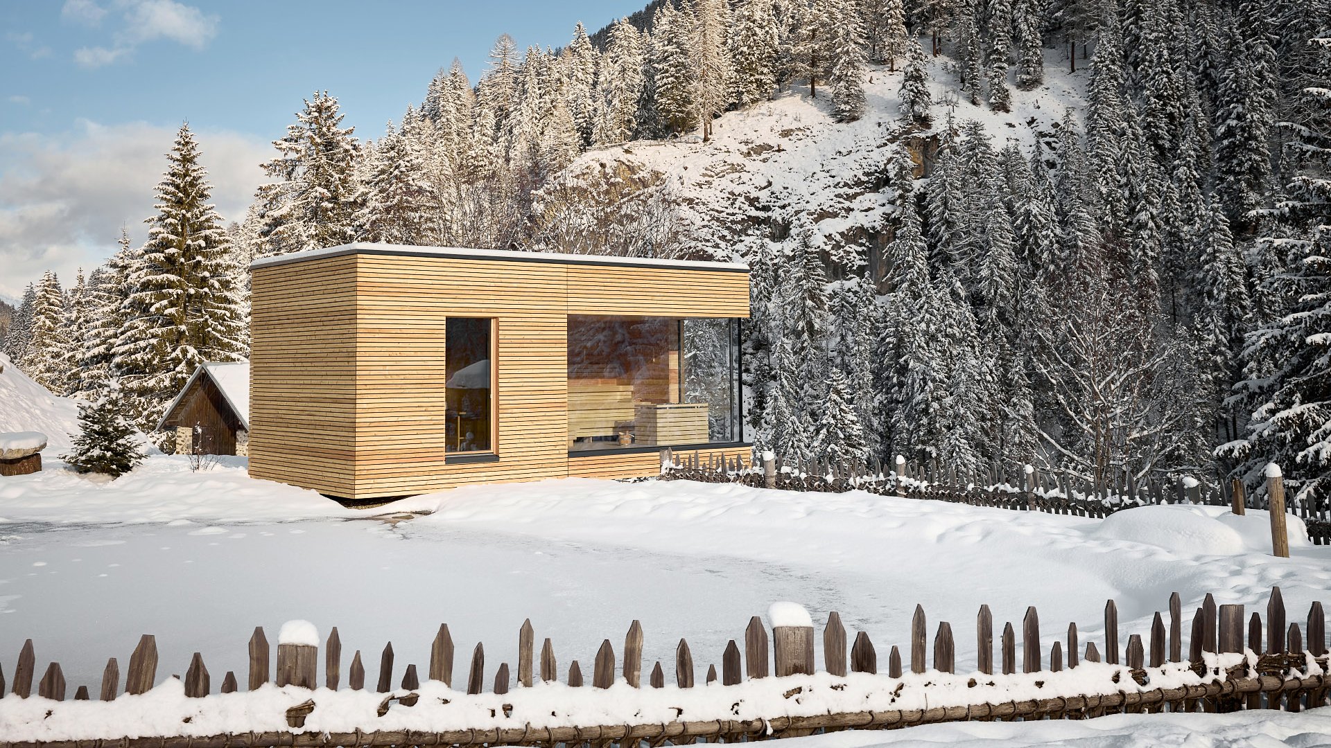 Außensauna im modernen Architekturstil des Wellnessbereiches, eingebettet in eine winterliche Landschaft mit schneebedeckten Bäumen und einem Berg im Hintergrund.